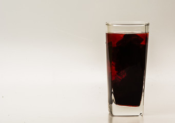 mixture of food coloring diffuse in water inside glass with empty copyspace area for slogan or advertising text message, over isolated grey background. 