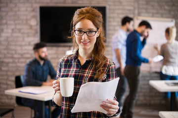 Portrait of young cute female designer holding cup of coffee