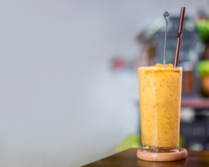 Blend orange juice on wooden table inside restaurant with blurry background