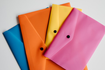 .Composition of four plastic envelopes of different colors on a white background. Back to school...