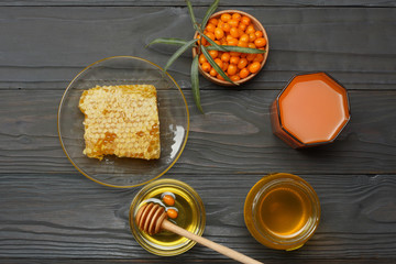 Sea buckthorn in wooden bowl, honey, Sea buckthorn juice on dark wooden table. top view with copy space