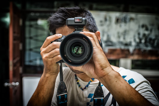 Close up portrait of photographer taking pictures with digital camera