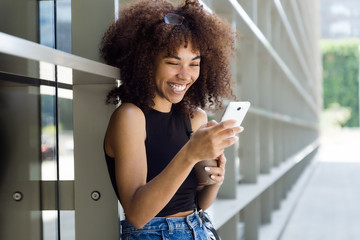 Beautiful young woman using her mobile phone in the street.