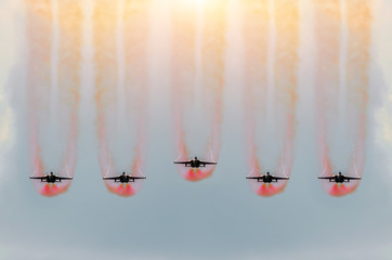 Five fighter jets fly together with red smoke