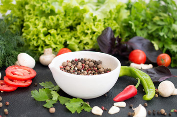 Fresh vegetables, greens and peppers peas in white bowl on dark background