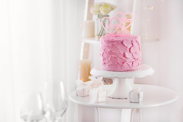 Stand with delicious cake for lesbian wedding and gifts on table