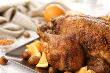 Tasty whole roasted turkey with sliced orange and hazelnuts on table