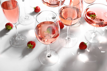 Many glasses of strawberry wine on white background