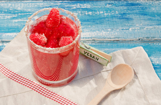 Bright crimson smoothies on a blue wooden background. Raspberry smoothies in a glass cup.Maline cocktail. Natural detoxification. A healthy diet. Liquid ice cream.