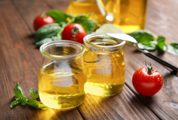 Jars with cooking oil and tomatoes on wooden table
