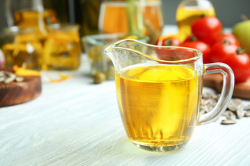 Jug with cooking oil on wooden table