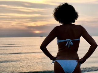 Beautiful young woman in bikini looking ocean 