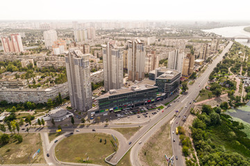Fototapeta na wymiar Residential district in a large metropolis with road junctions and houses. View of a newly built residential complex with a shopping center on the lower floors. Aerial view. From above