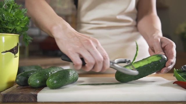 Chef peels cucumbers fof making vegetable salad with fresh greens, vegetarian dishes, cooking food, healthy nutrition