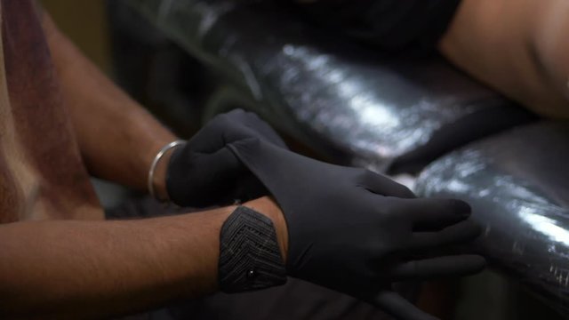 tattoo artist wears black gloves sterile. Preparing of master to work. Tattoo parlor. Man wears gloves. Male tattooist dresses black gloves on hands. Slow motion.
