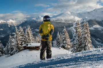 Fototapeta na wymiar Young skier standing on ski track looking on alps