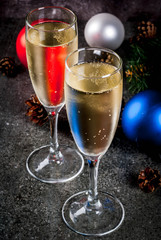Dry Champagne in glasses, Christmas colorful balls, pine cones, New Year still life composition on dark stone background, selective focus copy space
