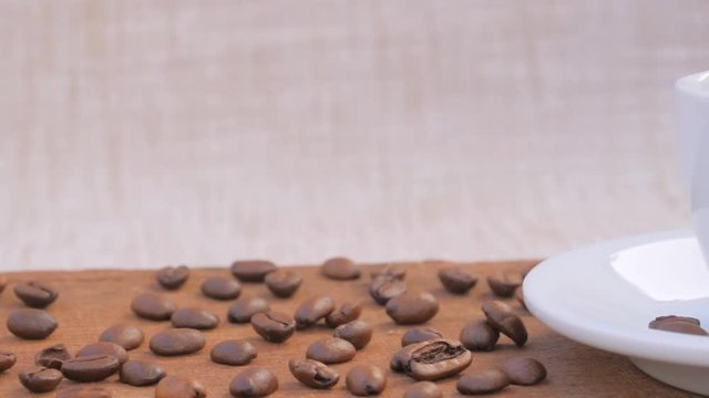 Aromatic smoking Hot Coffee cup and saucer on a wooden table with coffee beans