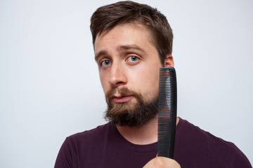 Young bearded man ready to comb his long messy beard - obrazy, fototapety, plakaty