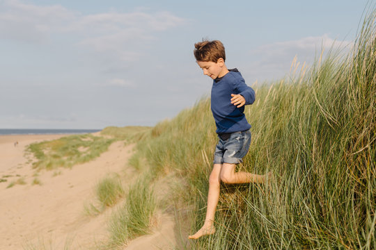 Joyful child jumps off a sand dune