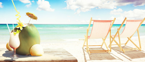 Sonnenliege mit Kokos und Cocktail am Strand