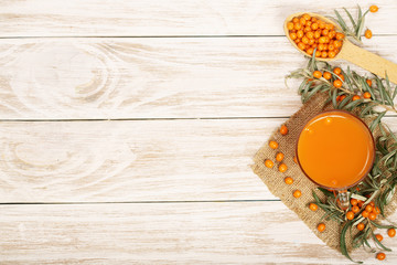 Sea buckthorn juice or tea with berries on a white wooden background with copy space for your text. Top view