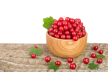 Red currant berries in wooden bowl on wooden table with white background