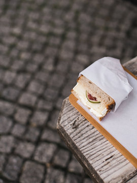 Sandwich with Camambert and fig wrapped in paper on the wooden street table