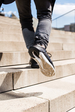 Feet in sport shoes stepping up the stairs