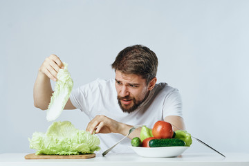 The man at the table is holding vegetables