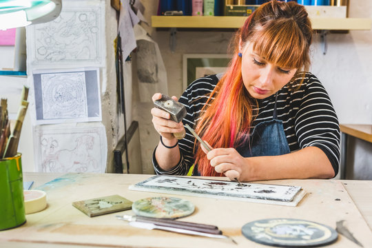 Artisan Woman Using Hammer and Chisel to Engrave a Slate Stone