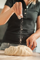 Woman hands knead dough on table in her home kitchen