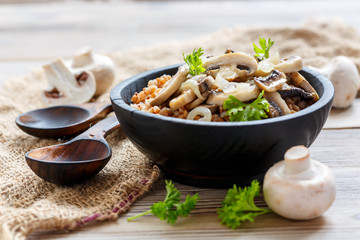 Buckwheat porridge with mushrooms and onions in a wooden bowl.