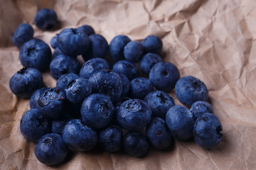 Blueberries on rustic wooden background, close up. Delicious berries on craft paper, macro