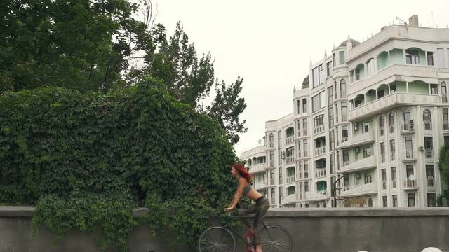 Beautiful woman in leggins riding her bicycle on the street slow motion