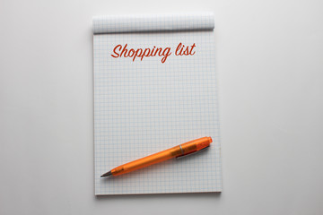 shopping list on  note book with orange pen