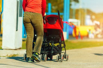 Obraz premium Woman strolling with a baby stroller in a park