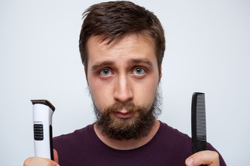 Young bearded man ready to trim, comb and sort out his long messy beard - obrazy, fototapety, plakaty