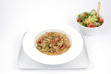 curry sauce on the plate of chicken with vegetables on a white background