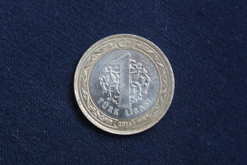 A coin worth 1 Turkish lira is on a dark background.