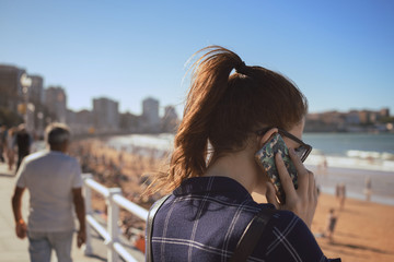 Young girl talking with her smatphone on the promenade