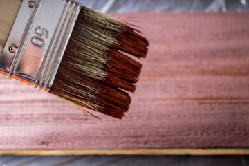 Brush with paint in hand. A man paints blue boards in a brown paint brush.