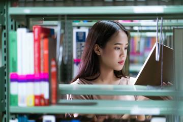 Asian women students books are selected from the bookshelf