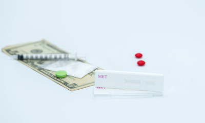 Two methamphetamine cassette test and plastic dropper with red and green drugs, fake heroin powders, american dollar bills and syringe and needle on white background with copy space