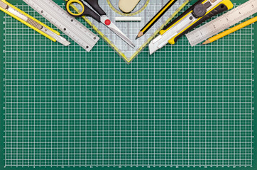 green cutting mat on desk with school or office supplies and tools