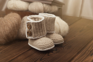Obraz na płótnie Canvas winter knitted booties ang yarn on wooden background, warm winter or autumn background