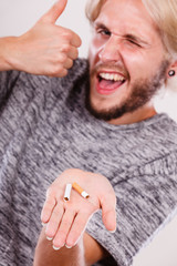 Man with broken cigarette on palm making thumb up