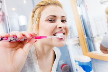 Woman brushing cleaning teeth in bathroom