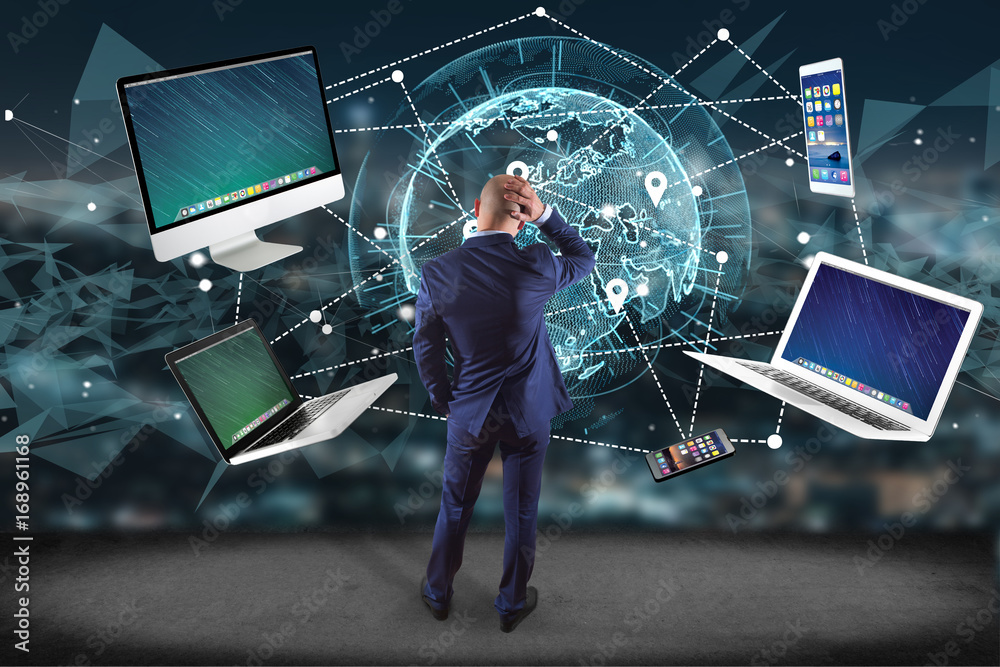 Poster businessman in front of a wall with computer and devices displayed on a futuristic interface with in