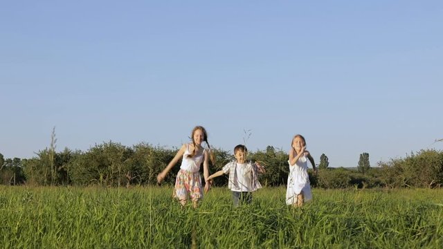 Three happy children playing in the field at the day time. Kid having fun outdoors. Concept of happy game.